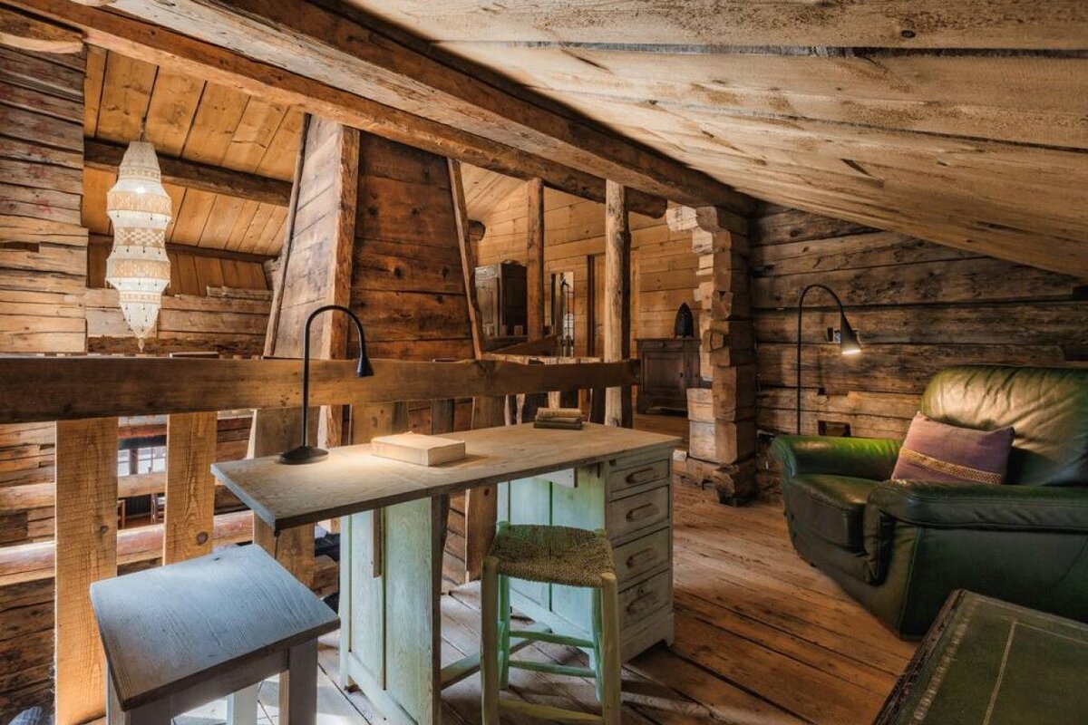 A wooden room with a green chair and a desk