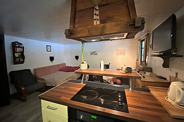 A kitchen with a stove top oven and a chair
