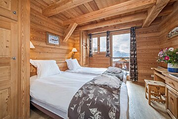 A bedroom with two beds and a window with mountains in the background
