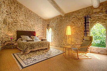 A bedroom with a large bed and a chair