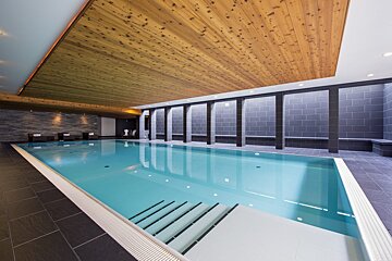 A large indoor swimming pool with a wooden ceiling