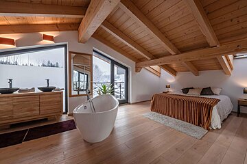 A bedroom with a bathtub and a large window