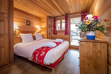 A bedroom with a bed and a vase of flowers