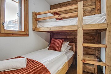 A bunk bed with white sheets and a red pillow