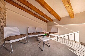 A white chair with a brown pillow sits next to a white table