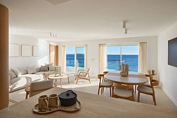 A living room and dining room with a view of the ocean