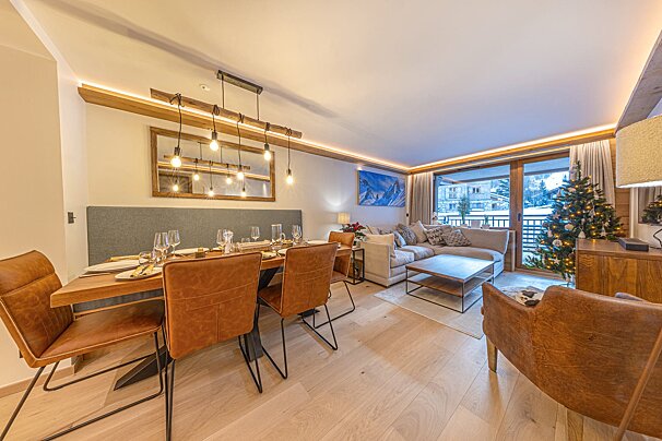 A warm and inviting open-plan living and dining room with a festive Christmas tree, large windows, and modern rustic decor.