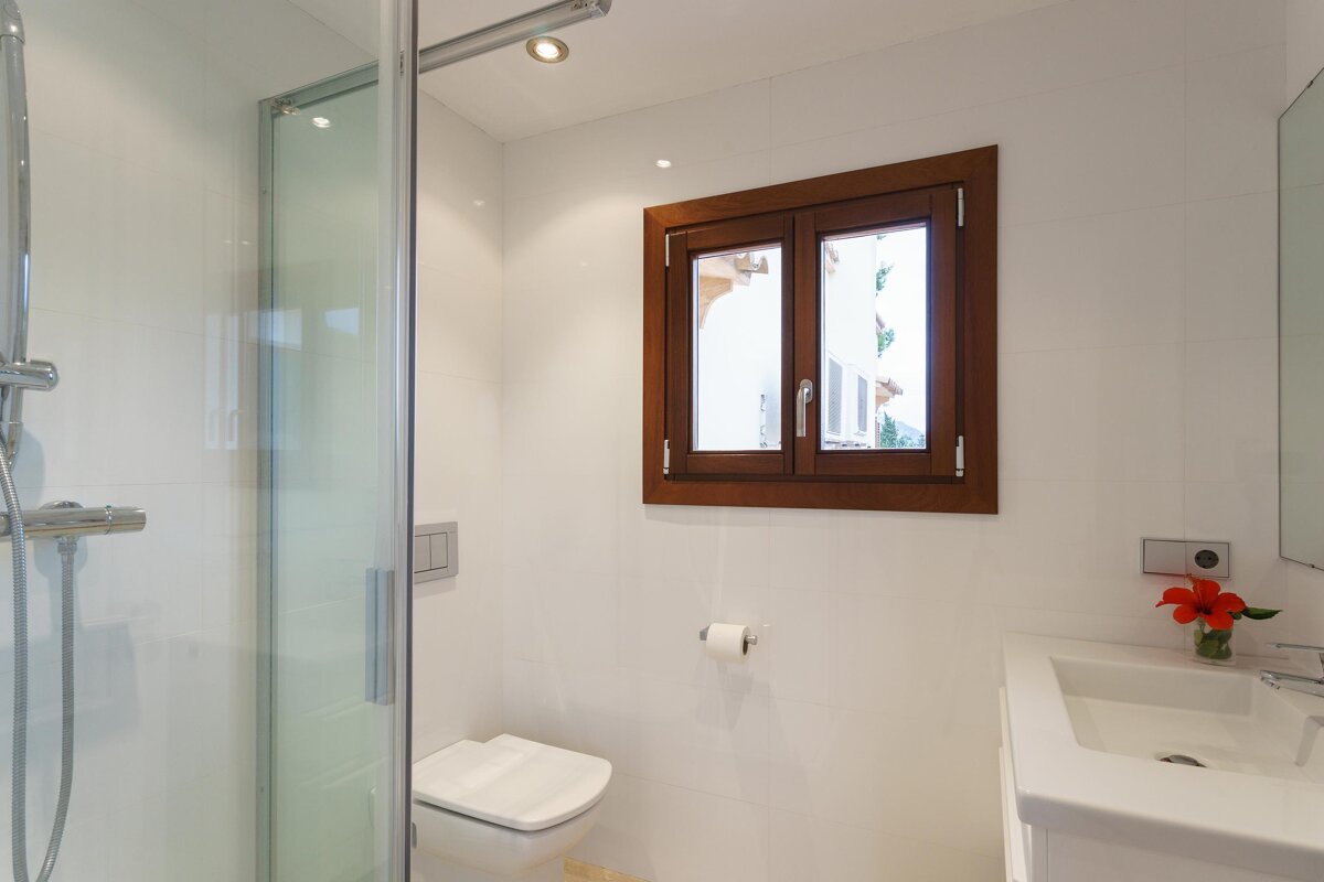 A bathroom with a toilet a sink and a window