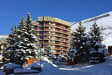 Snow covered trees in front of a building with balconies