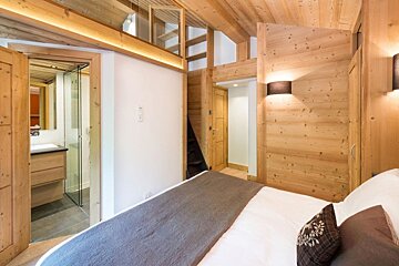 A bedroom with wooden walls and a bed
