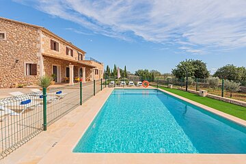 A large swimming pool in front of a stone house