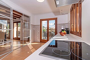 A kitchen with a stove top oven and a bowl of fruit on the counter