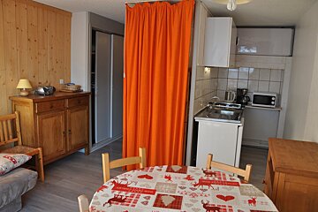 A kitchen with a table and chairs and an orange curtain