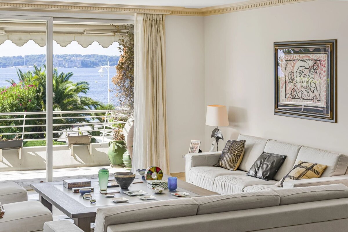 Bright living room with a white sofa and sliding glass doors opening to a balcony with beautiful sea views.
