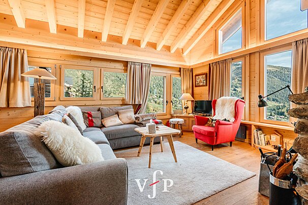 A living room with a couch and a red chair with the letter v on the bottom