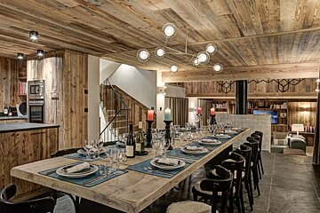 A long wooden table with plates and glasses on it