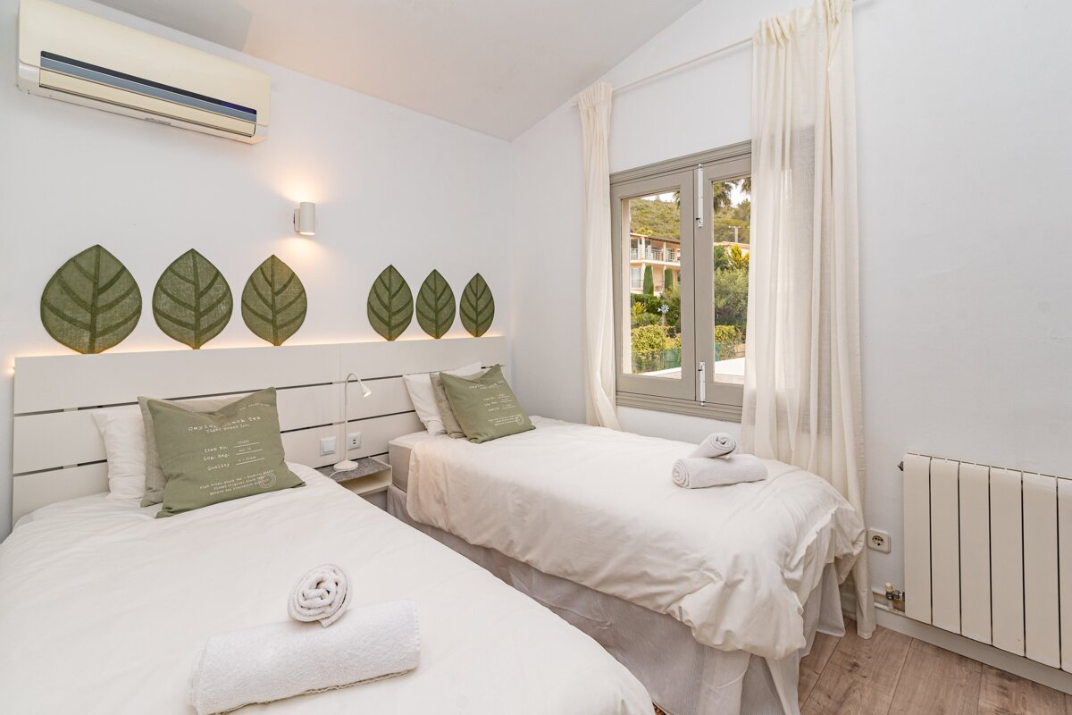 A bedroom with two twin beds and a window