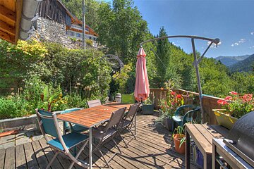 A wooden deck with a table and chairs and a pink umbrella
