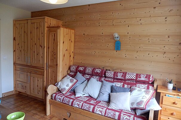A wooden couch with a red and white blanket on it
