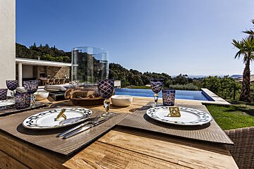 Plates and glasses on a table with a view of a pool