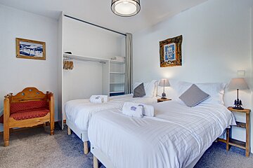 A bedroom with two beds and a picture on the wall