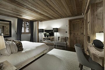 A bedroom with a wooden ceiling and a large bed