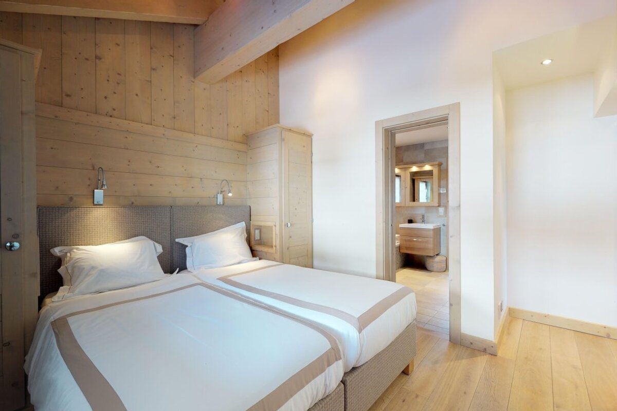 A bedroom with two beds and a bathroom in the background