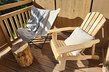 A wooden deck with two chairs and a stool