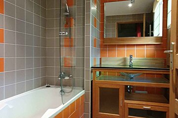A bathroom with orange and gray tiles and a sink