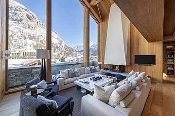 A living room filled with furniture and a fireplace with mountains in the background