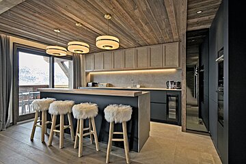 A kitchen with furry bar stools and wooden cabinets