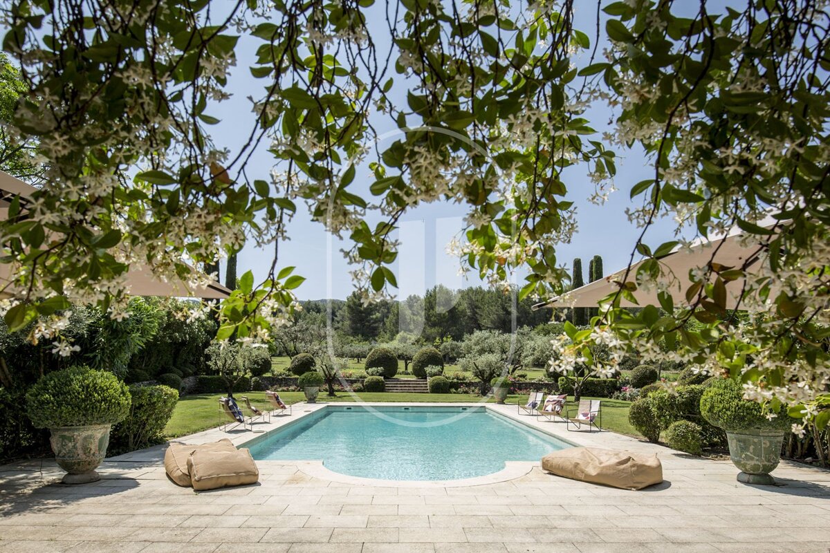 A large swimming pool is surrounded by chairs and umbrellas