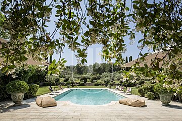 A large swimming pool is surrounded by chairs and umbrellas