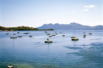 A large body of water filled with boats and mountains in the background