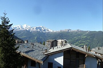 A rooftop view of a mountain range with buildings in the foreground