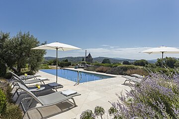 A large swimming pool is surrounded by chairs and umbrellas