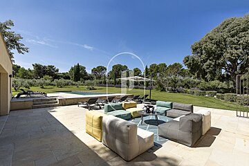 A patio with a lot of furniture and a pool in the background
