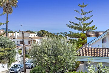 A car is parked in front of a house with a view of the ocean