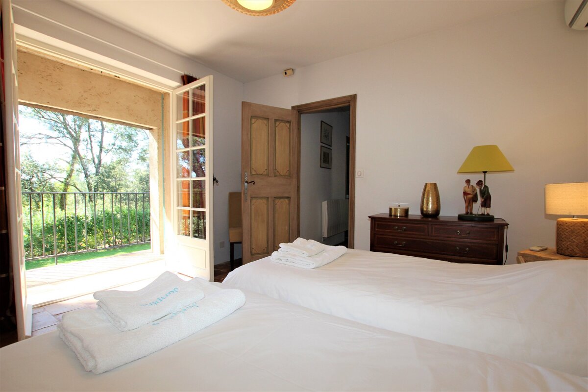 A bedroom with two beds a dresser and a lamp