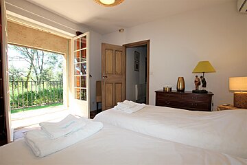 A bedroom with two beds a dresser and a lamp