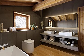 A modern-rustic bathroom with dark walls, wooden beams, a snowy window view, dual sinks, and warm wood flooring.
