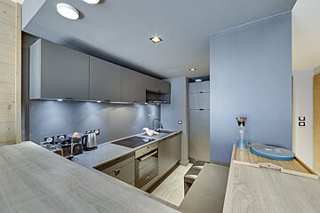 A kitchen with gray cabinets and a blue wall
