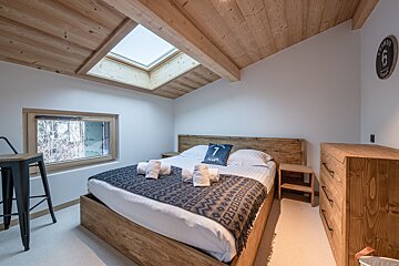A bedroom with a bed and a clock that has the number 7 on it