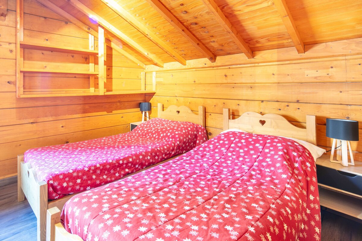 A bedroom with two beds and two lamps