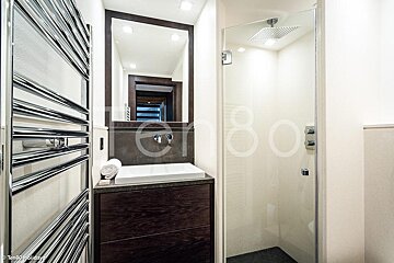 A bathroom with a sink and a shower with the number 80 on the wall