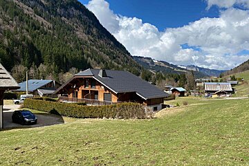 A car is parked in front of a house in the mountains