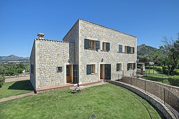 A large stone house with green shutters on the windows