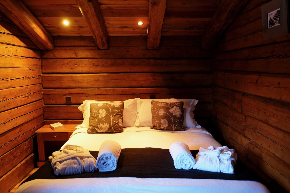 A bed in a wooden cabin with pillows and towels