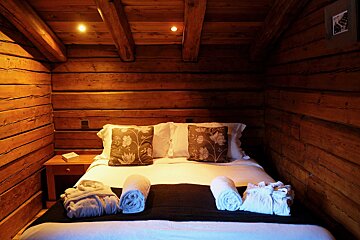 A bed in a wooden cabin with pillows and towels