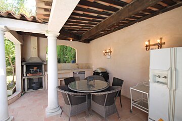 A patio with a table and chairs and a refrigerator